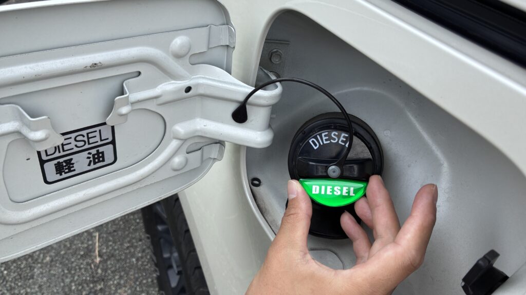 デリカD5の給油キャップに緑のDIESELエンブレムを貼っているところ